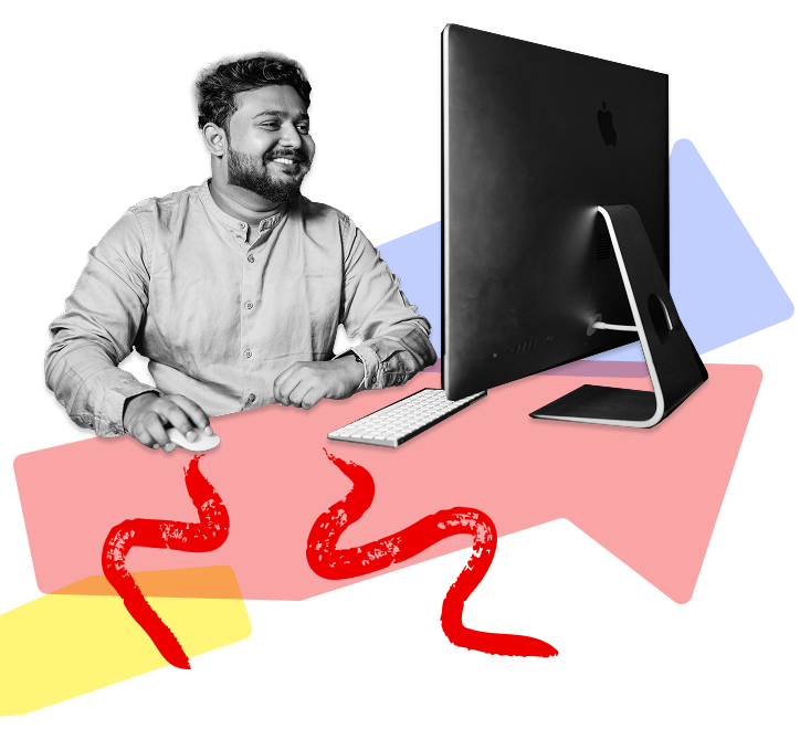 Man sitting at his desk smiling and looking at this computer screen while using a mouse