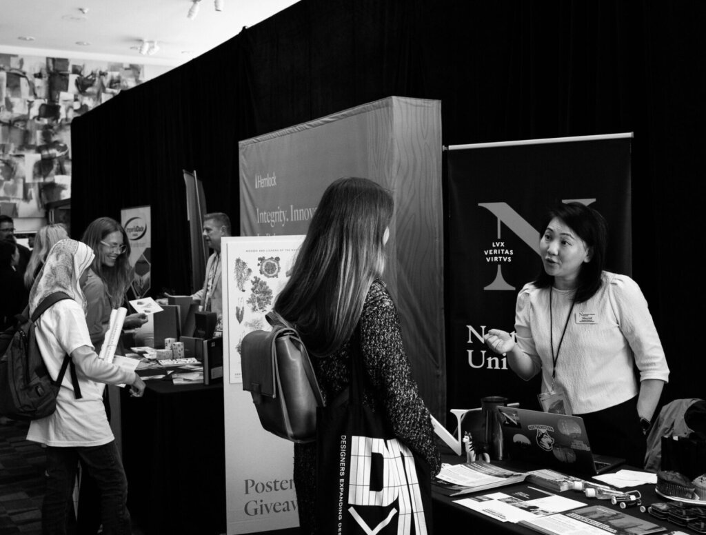 Exhibitors standing at tables and interacting with conference attendees