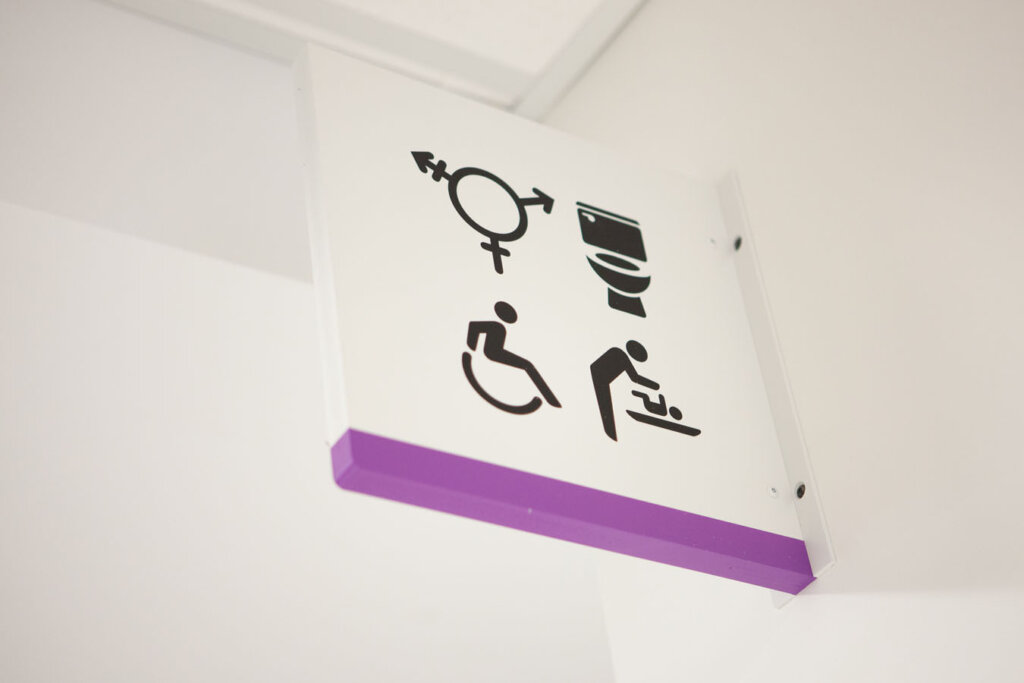 Example of amenity directional signage with gender inclusive pictogram.