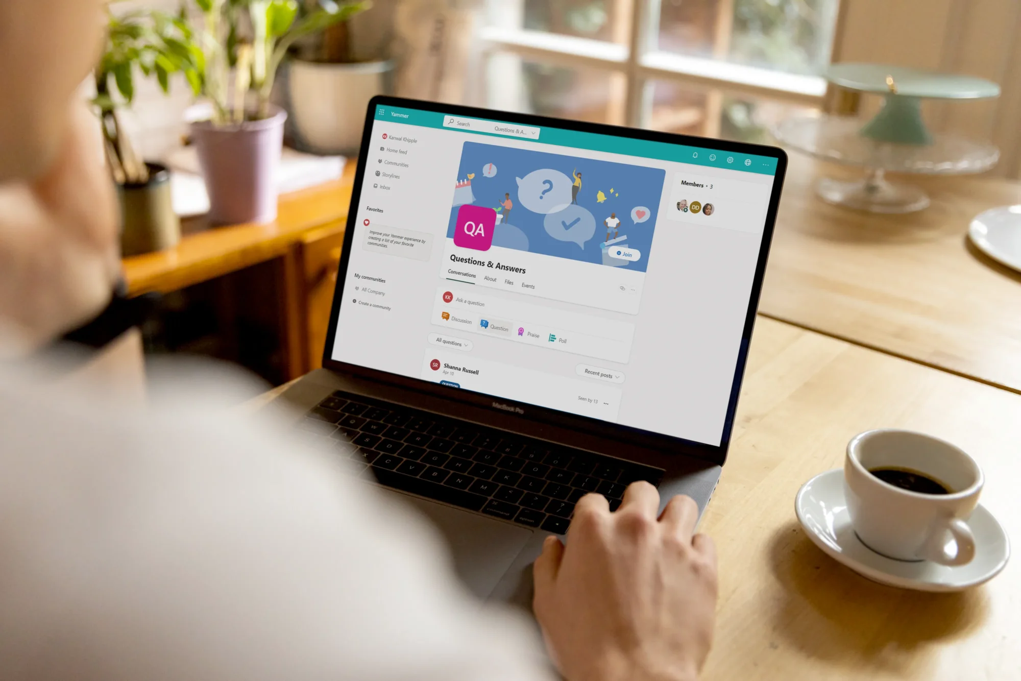 A person browsing through a laptop in a wooden table with a cup of coffee